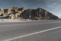 a long street with mountains in the background and rocks at the edge, both yellow