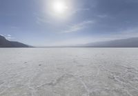 a view of the sun shining on the horizon of a deserted plain with many ice crystals