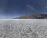 a panoramic image shows a view of the water in a desert area, with mountains in the background