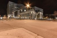 the lights of city buildings are lit up from the dark sky in an empty, deserted street