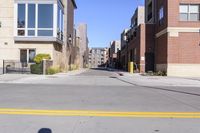 a large open street between some tall buildings and apartments in the background that is on a sunny day