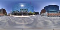 an abstract image of a building in a city with curved glass and concrete surfaces along the street