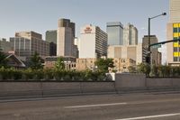 a long highway with two cars driving on it and tall buildings in the distance with trees in the foreground