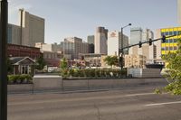 a long highway with two cars driving on it and tall buildings in the distance with trees in the foreground