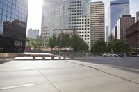 there are cars driving on the street in a city that has high buildings next to it