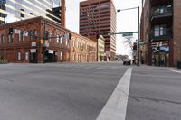 an intersection with street signs and car driving on the road near buildings on the other side