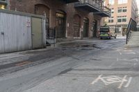 a green trash truck parked in a parking spot on a city street next to an industrial building