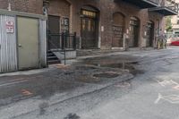 a green trash truck parked in a parking spot on a city street next to an industrial building