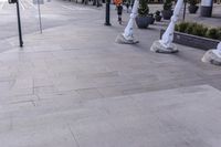 many statues are near each other on the sidewalk with buildings in the background with trees