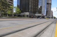 two trains are near the sidewalk and some buildings with glass windows above it, one has yellow cabs