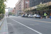 a row of parked cars in the middle of a street with scaffolding above