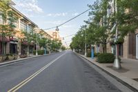 empty street with buildings and trees on both sides of the road in a neighborhood with high - rise apartment homes and streets