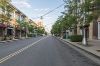 empty street with buildings and trees on both sides of the road in a neighborhood with high - rise apartment homes and streets