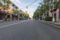 empty street with buildings and trees on both sides of the road in a neighborhood with high - rise apartment homes and streets