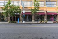 an empty city street and two buildings with some signs above them to show customers the number of customers, including one car