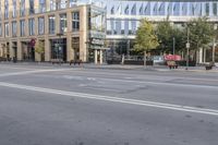 an empty street with buildings and green signs in the background with a person crossing an intersection