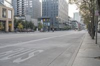 a empty street near some big buildings and trees near a curb sign reading stop on the sidewalk