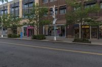 a paved city street is lined with buildings and trees along with green plants and bushes