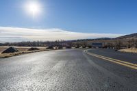 a empty highway with several signs on the side of it and a bright sun shines in the sky