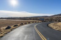 a empty highway with several signs on the side of it and a bright sun shines in the sky