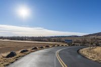 a empty highway with several signs on the side of it and a bright sun shines in the sky