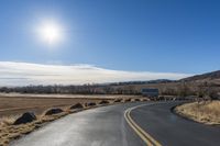 a empty highway with several signs on the side of it and a bright sun shines in the sky