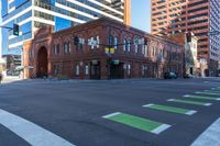 a very tall building with several windows at an intersection in the city, green marking the street
