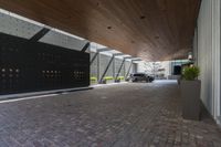 a parking garage with an attached driveway outside of a building with wood ceilings, with a car in front and outside