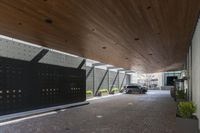 a parking garage with an attached driveway outside of a building with wood ceilings, with a car in front and outside