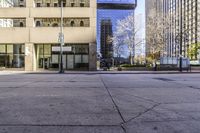 a view of a group of tall buildings through a city sidewalk in the afternoon sun