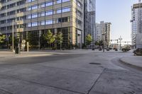 a concrete walkway next to building, a sidewalk and an empty parking spot, with trees in the foreground