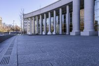 the building has large pillars and glass walls in it's windows with columns on the side