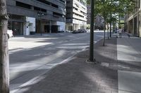 a sidewalk with trees on each side of it that is shaded by buildings on the right