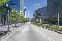 an empty city street in the middle of town, near tall buildings and trees and people walking on either side