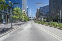 an empty city street in the middle of town, near tall buildings and trees and people walking on either side