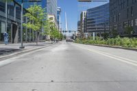 an empty city street in the middle of town, near tall buildings and trees and people walking on either side