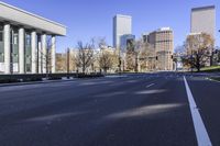 empty street with tall buildings and columns in the background at an angle, near park benches