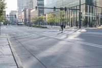 people ride their skateboards down an empty city street, with buildings on the other side