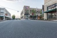 a wide empty street is shown in front of stores, and businesses in the background