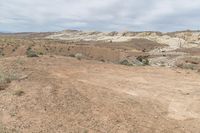 the young boy is jumping for the frisbee in the desert area of a landscape