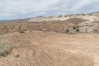 the young boy is jumping for the frisbee in the desert area of a landscape