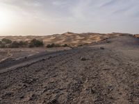 a truck on a dirt road in the desert with rocks and stones on the ground