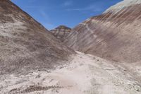 two women riding horses through the desert near mountains and hills with dirt floors and steep cliffs