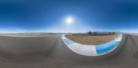 a skate boarder in black shirt riding on a road in the desert under a bright blue sky