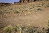 an open dirt road through the desert with rocky mountains in the distance in the distance