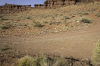 an open dirt road through the desert with rocky mountains in the distance in the distance