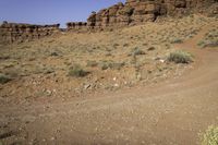 an open dirt road through the desert with rocky mountains in the distance in the distance