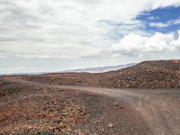 an image of a dirt road in the desert setting looking out on the horizon near some mountain