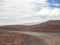 an image of a dirt road in the desert setting looking out on the horizon near some mountain