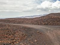 an image of a dirt road in the desert setting looking out on the horizon near some mountain